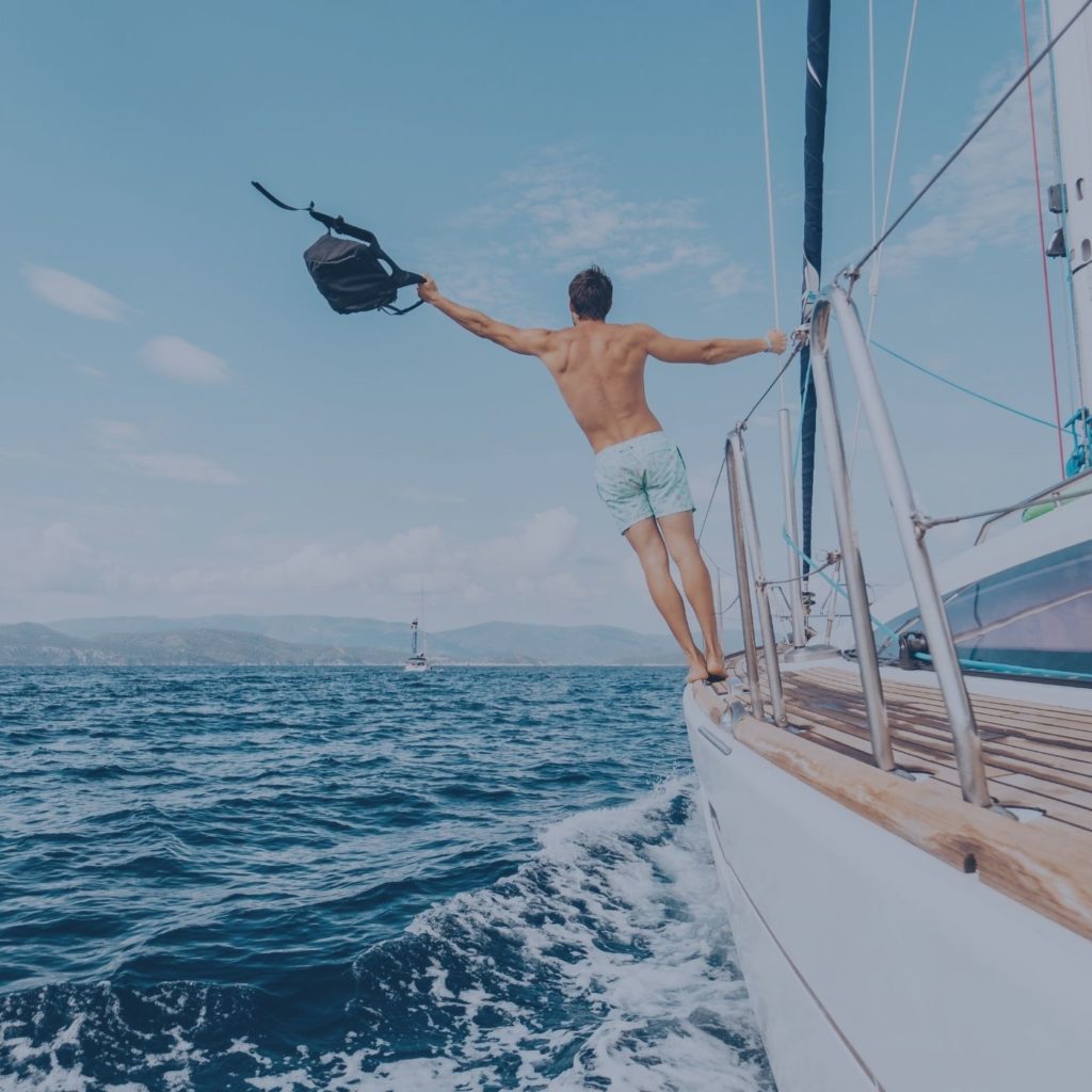 man hanging off of a sailboat